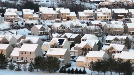 Dense-suburban-neighborhood-with-beige-houses-covered-in-snow-at-sunset