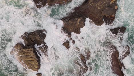 Waves-crashing-on-rocks-in-nervi,-genoa,-italy,-with-the-turquoise-sea,-aerial-view