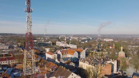 Aerial-establishing-view-of-Kuldiga-Old-Town-,-houses-with-red-roof-tiles,-telecommunication-tower,-sunny-winter-day,-travel-destination,-wide-drone-shot-moving-forward