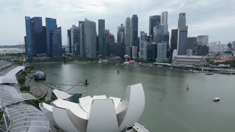 aerial-drone-shot-of-Art-and-Design-Building-In-ultramodern-cityscape-of-Singapore,-along-the-Marina-Bay
