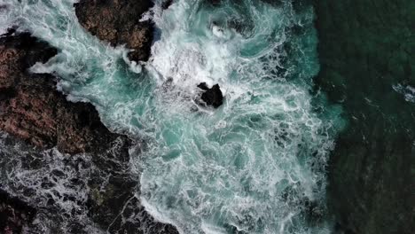 Turbulent-waves-crashing-against-rocky-shores-of-Corralejo,-Fuerteventura-in-the-Canary-Islands,-aerial-view