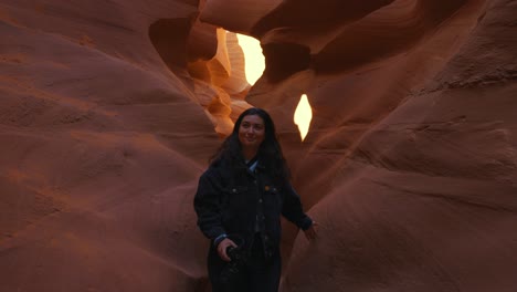 Young-woman-walking-at-Antelope-Canyon,-Arizona,-smooth-wavy-sandstone-walls