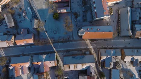 Aerial-establishing-view-of-Kuldiga-Old-Town-,-houses-with-red-roof-tiles,-sunny-winter-day,-Liepajas-street-from-above,-travel-destination,-wide-birdseye-drone-shot-moving-right