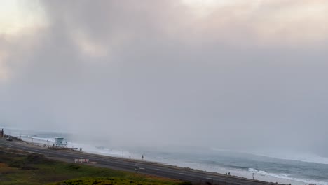 Während-Eines-Sonnenuntergangs-Rollte-Schnell-Nebel-Auf,-Der-Die-Küste,-Die-Autobahn-Und-Die-Menschen-Am-Strand-Bedeckte