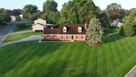 Aerial-view-of-a-brick-house-with-green-lawn-and-trees-in-a-suburban-setting