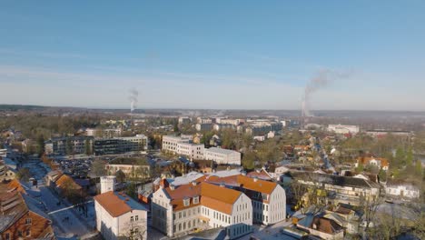Aerial-establishing-view-of-Kuldiga-Old-Town-,-houses-with-red-roof-tiles,-telecommunication-tower,-sunny-winter-day,-travel-destination,-wide-drone-shot-moving-backward
