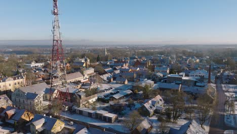 Aerial-establishing-view-of-Kuldiga-Old-Town-,-houses-with-red-roof-tiles,-telecommunication-tower,-sunny-winter-day,-travel-destination,-wide-drone-shot-moving-forward