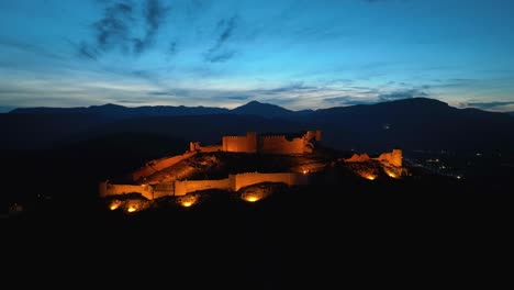 Aerial-footage-of-an-illuminated-castle-on-top-of-the-hill-at-dusk
