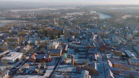 Aerial-establishing-view-of-Kuldiga-Old-Town-,-houses-with-red-roof-tiles,-sunny-winter-day,-travel-destination,-wide-drone-shot-moving-forward
