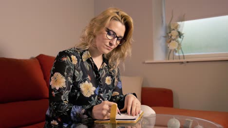 Woman-writing-at-home-wearing-floral-shirt