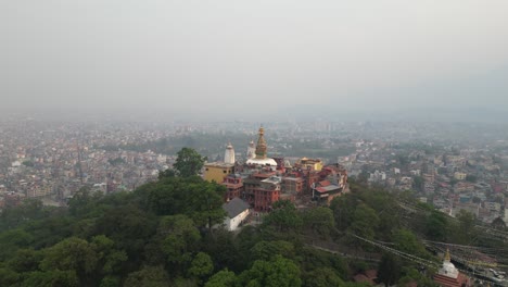 aerial-drone-shot-zooming-in-on-buddha-temple-on-a-hill-In-Kathmandu,-Nepal-at-the-base-of-the-Himalayas
