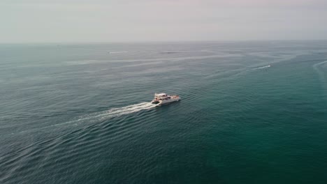 Barco-Solitario-Navegando-Por-Las-Tranquilas-Aguas-Cerca-De-Puerto-Banús,-Marbella-Bajo-Un-Cielo-Despejado,-Vista-Aérea