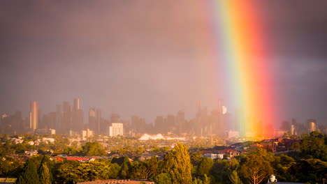 Melbourne-Victoria,-Australia-skyline-on-a-cloudy-day-with-rain-passing-and-rainbow-appearing-in-the-distance