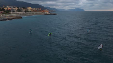 Kitesurfista-Deslizándose-Sobre-Las-Aguas-Azules-Del-Mar-Frente-A-La-Costa-De-Génova,-Italia-Al-Atardecer,-Serena-Escena-Oceánica