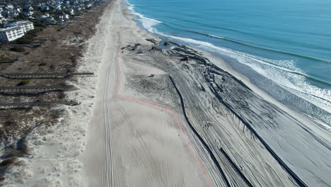 Drone-shot-of-beach-nourishment,-or-adding-sand-or-sediment-to-beaches-to-combat-erosion,-can-have-negative-impacts-on-wildlife-and-ecosystems,-with-water-coming-out-of-pipe