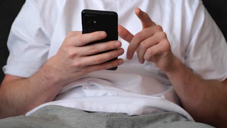 man-scrolling-his-smartphone-while-sitting-on-sofa