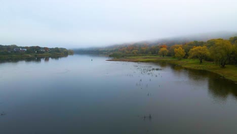 Luftaufnahme-über-Dem-Fluss-Nemunas-Mit-Dichtem,-Farbenfrohem-Wald-Und-Häusern-Am-Flussufer-Bei-Sonnenaufgang-Im-Herbst