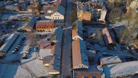 Aerial-establishing-view-of-Kuldiga-Old-Town-,-houses-with-red-roof-tiles,-Liepajas-street,-sunny-winter-day,-travel-destination,-wide-drone-shot-moving-forward,-tilt-up