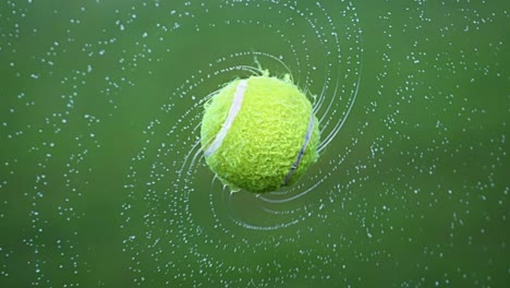 Nasser-Tennisball-Mit-Fliegenden-Wassertropfen-Im-Hintergrund