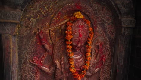 Pintura-Roja-Y-Naranja-En-La-Estatua-De-Un-Dios-Del-Templo-En-Katmandú,-Nepal,-En-La-Base-Del-Himalaya.