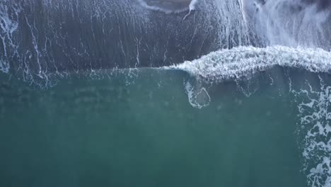 Top-down-drone-footage-of-waves-crashing-on-a-beach