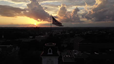 Drohne-Umkreist-Bei-Sonnenuntergang-Einen-Turm-Mit-Einer-Amerikanischen-Flagge