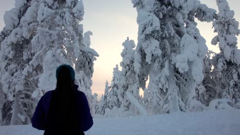 Girl-Admires-Beautiful-Snow-Covered-Forest-in-Lapland,-Finland,-Arctic-Circle