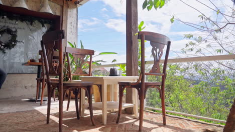 Gemütliches-Café-Interieur-Auf-Einem-Balkon,-Geschmückt-Mit-Holzstühlen-Und-Tischen,-Die-An-Einem-Frühlingstag-Eine-Warme-Atmosphäre-Schaffen