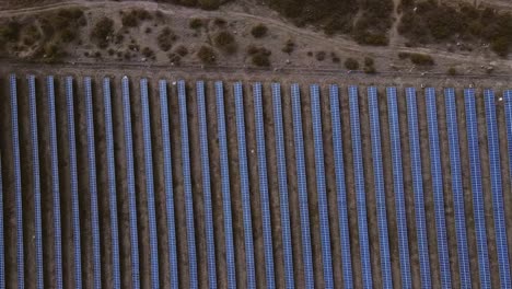 Aerial-slow-motion-of-symmetrical-solar-panel-rows-in-rural-area,-aerial-top-view