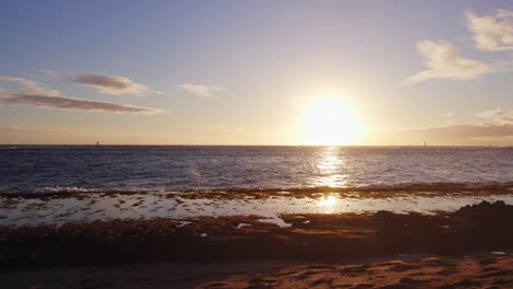 Schwenk-Nach-Links-über-Den-Weiten-Pazifischen-Ozean,-Von-Der-Strahlend-Weißen-Untergehenden-Sonne-Zum-Schattigen-Ufer,-Das-Kurz-Vor-Sonnenuntergang-Auf-Oahu,-Hawaii,-Das-Rosafarbene-Alpenglühen-Offenbart