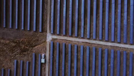 Dolly-in-aerial-glides-over-symmetrical-solar-panels-in-a-rural-farming-field