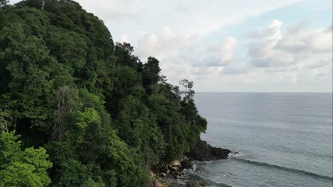 Flying-next-to-Costa-Rica-shore-alongside-a-green-leafy-cliff