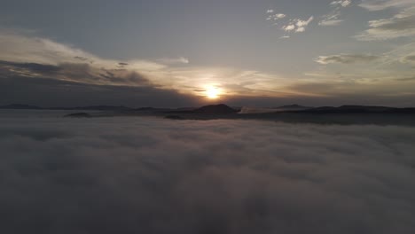 Escena-Delantera-Sobre-Las-Nubes-Con-Una-Puesta-De-Sol-Y-Montañas-Al-Fondo
