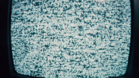 Old-TV-with-static-on-display,-blinking-in-a-dark-room