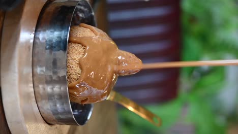 Vertical-Footage:-Pouring-caramel-sauce-on-Knafeh-ball-dessert,-Close-up-of-Knafeh,-Arabic-sweets