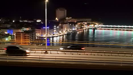 Cars-rush-over-Queen-Juliana-Bridge-at-night,-Handelskade-and-Queen-Emma-bridge-in-view