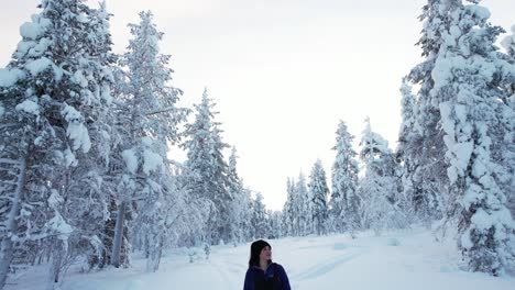 Girl-Walking-In-Wintery-Forest,-Admiring-the-Beauty-and-Trees-in-Lapland,-Finland,-Arctic-Circle