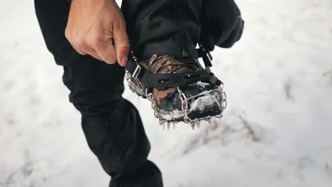 a-hiker-trying-to-put-crampon-on-his-winter-boots
