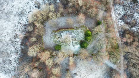Scenic-aerial-descend-over-ancient-church-remains-with-seats-and-green-fir-tree