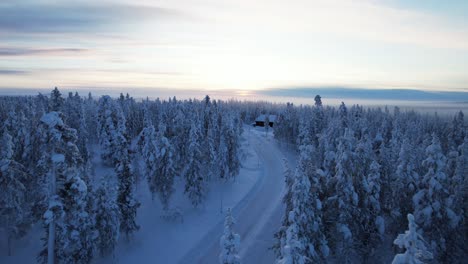 Drone-Flies-Over-Snowy-Winter-Forest-At-Dusk-in-Lapland,-Finland,-Arctic-Circle