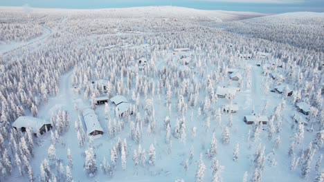 Entorno-Aéreo-De-Paisaje-De-Bosque-Nevado-Y-Cabañas-En-Laponia,-Finlandia,-Círculo-Polar-ártico