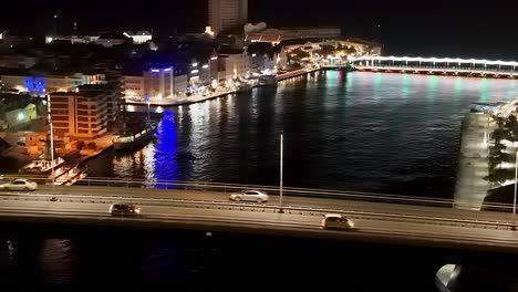 Handelskade-buildings-illuminated-at-night,-view-from-Queen-Juliana-Bridge-aerial
