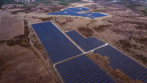 Massive-solar-energy-power-station,-aerial-view-over-solar-panel-array-and-rural-fields