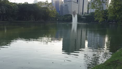 Reflexión-Del-Edificio-Moderno-En-El-Agua-Del-Lago-En-El-Parque-Lumpini-Bangkok-Tailandia