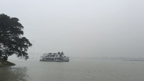 Static-shot-of-a-passenger-ferry-sailing-on-Hooghly-river-with-background-barely-seen-in-Kolkata,-India