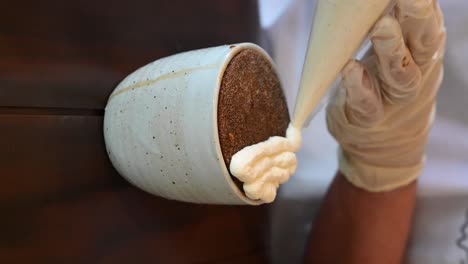 Vertical-Footage:-Applying-fresh-cream-on-a-coffee-latte,-Close-up-of-the-coffee-cup