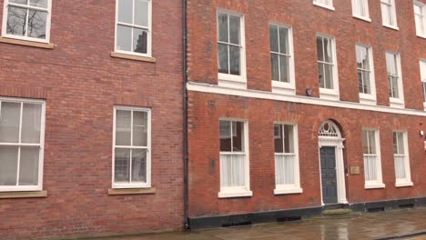 Brick-architecture-of-a-building-beside-wet-street-during-rainy-day-in-Manchester,-England