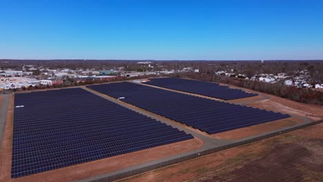 An-aerial-view-over-a-large-solar-field-on-Long-Island,-New-York-on-a-sunny-day-with-blue-skies-and-no-clouds