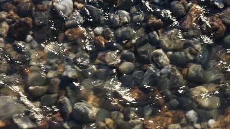 Das-Kristallklare-Wasser-Des-Flusses-Arrow-In-Warwickshire,-England,-Das-über-Verschiedenfarbige-Steine-Und-Kieselsteine-Im-Flussbett-Fließt