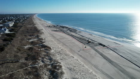 Aerial-shot-of-beach-nourishment,-or-adding-sand-or-sediment-to-beaches-to-combat-erosion,-can-have-negative-impacts-on-wildlife-and-ecosystems,-with-water-coming-out-of-pipe